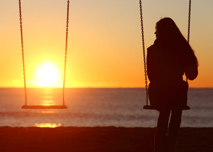 wife sitting alone on a swing set for two.