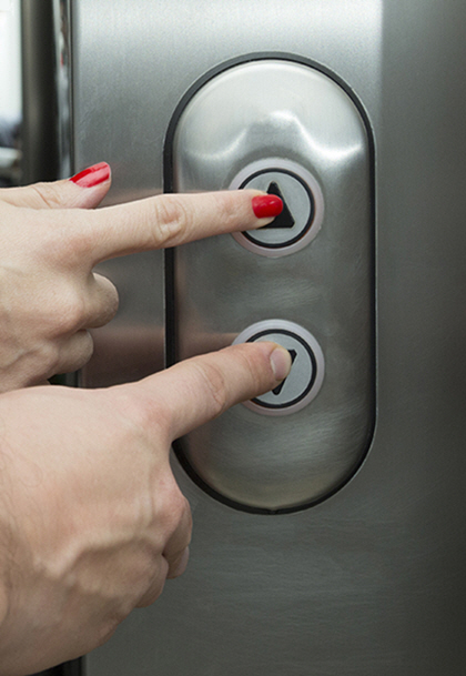 Two hands pressing an elevator button